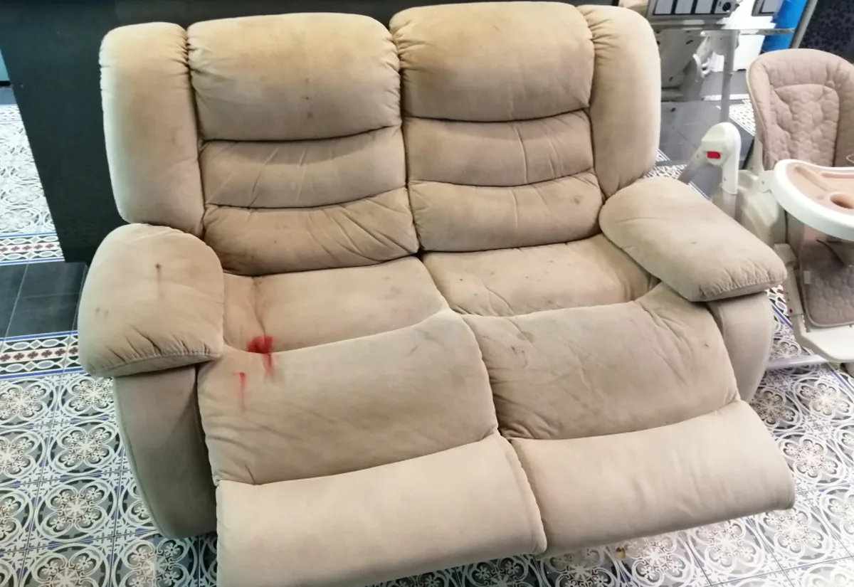 The same fabric recliner before cleaning &mdash; grubby, greyed seats and a red spill on the left cushion.